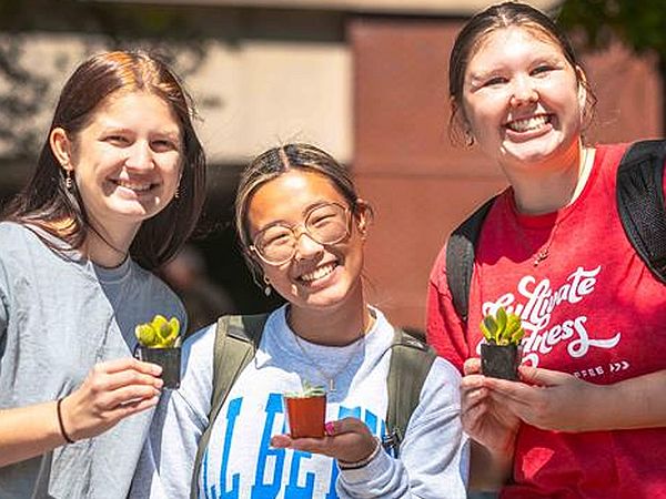 3 students holding potted plants